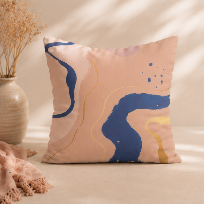 Warm neutral cushion cover with abstract shapes in beige, blue, and gold tones on a decorative pillow