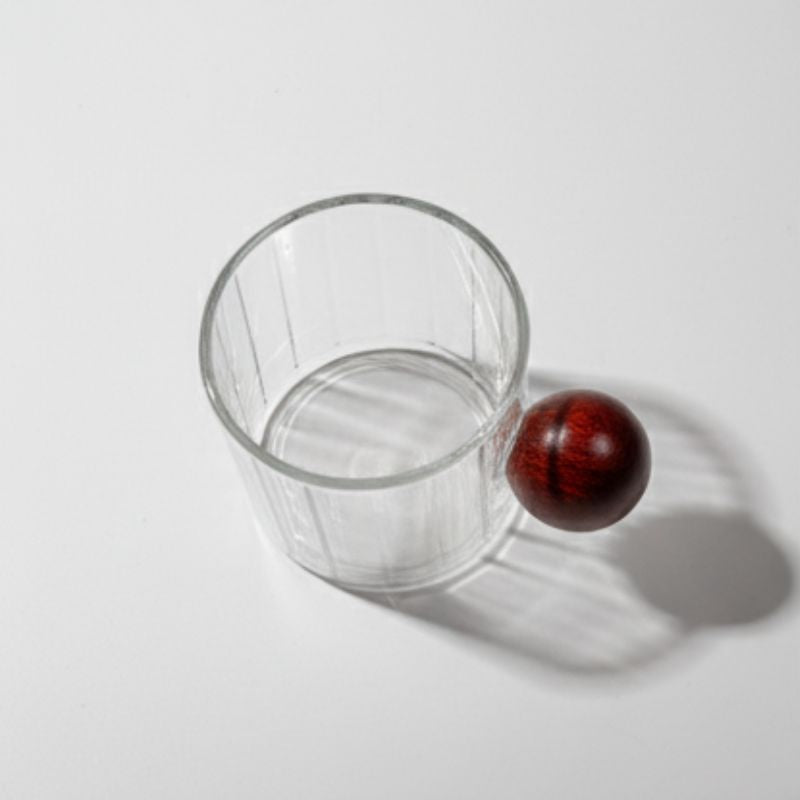 Ribbed glass mug with wooden ball handle on white background
Modern artistic coffee cup with ribbed glass body
Transparent glass mug with unique round wooden handle
Designer borosilicate glass mug for coffee or tea