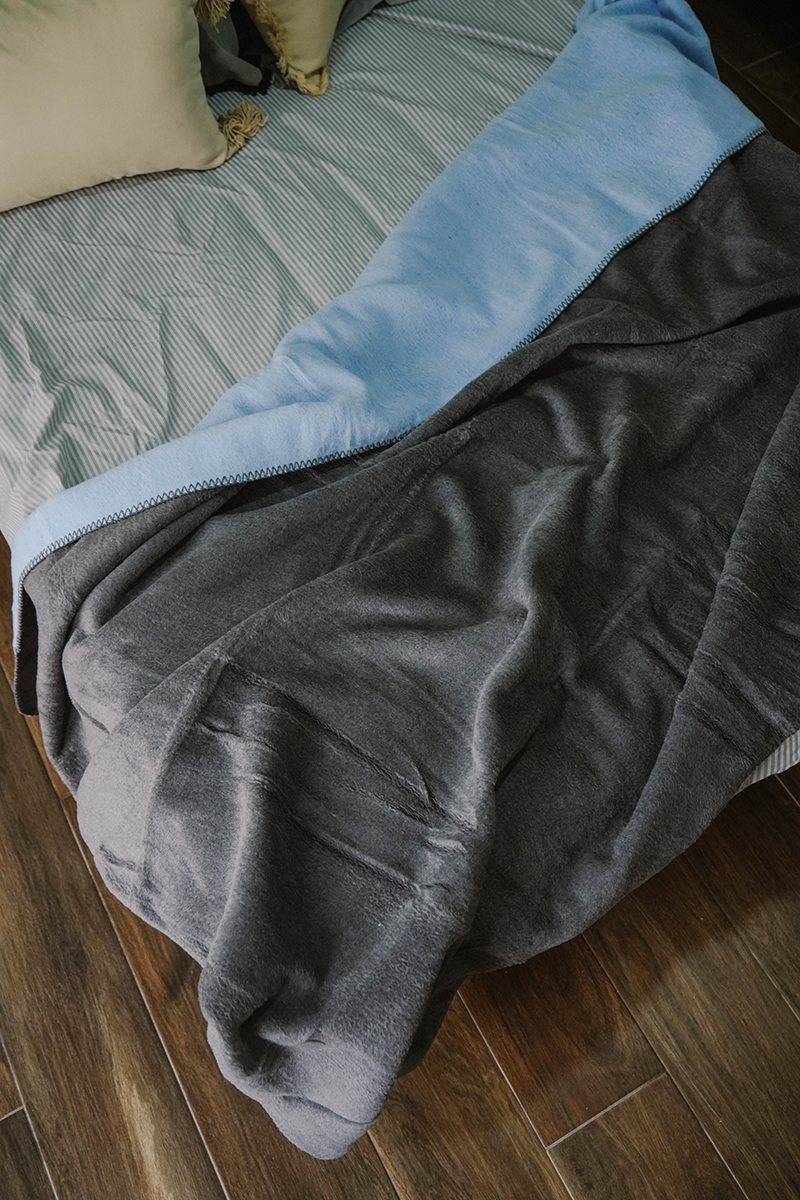 Double-face fleece blanket in pink and grey draped on chair