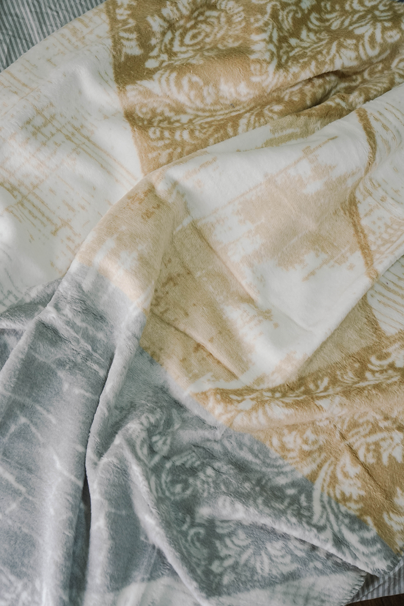 Geometric beige and grey fleece blanket draped on wooden rod