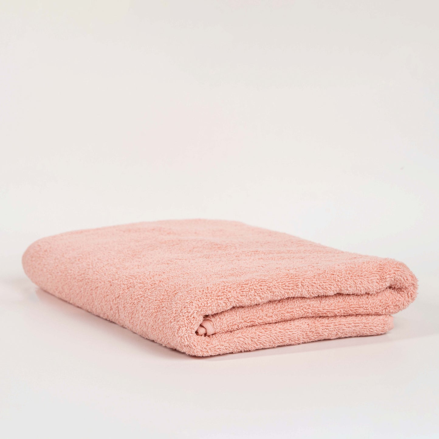 Absorbent blush pink cotton towel folded neatly.