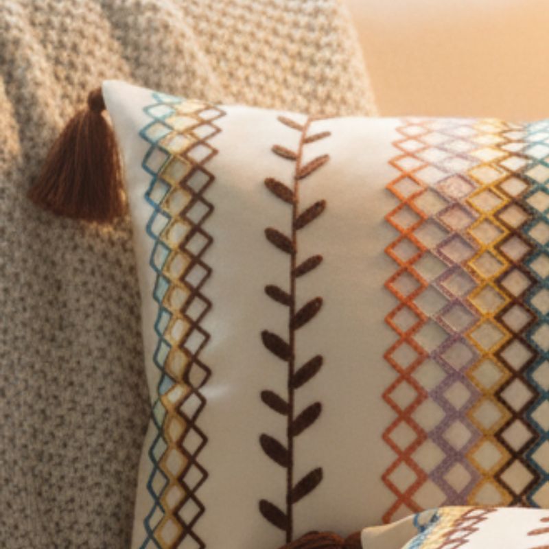 Square boho cushion cover with multi-color embroidered geometric and leaf pattern, finished with brown tassels on all four corners, 43x43 cm