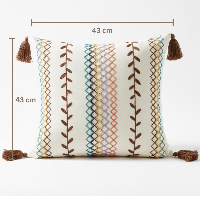 Square boho cushion cover with multi-color embroidered geometric and leaf pattern, finished with brown tassels on all four corners, 43x43 cm