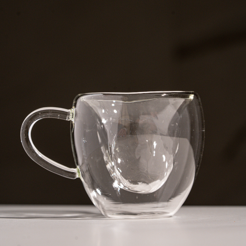 Double-wall glass coffee cup with rounded design and handle
Transparent insulated glass mug for espresso or tea
Modern borosilicate glass coffee cup on white background
Heat-resistant double-wall clear coffee cup