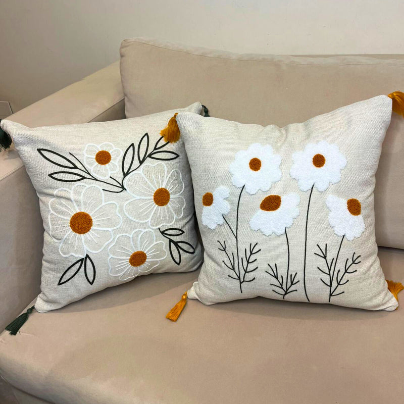 Square embroidered daisy cushion cover with tassels on beige sofa