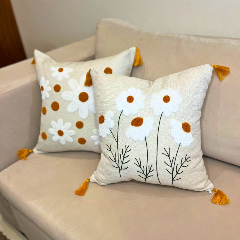 Square embroidered daisy cushion cover with tassels and white floral design on beige sofa