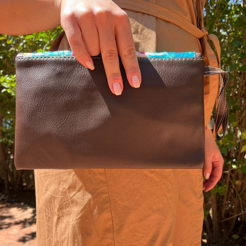 Woman wearing a brown leather shoulder bag with colorful floral embroidered flap outdoors