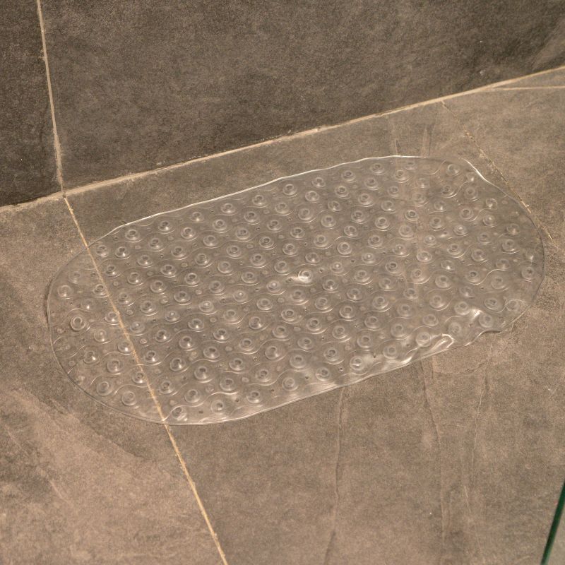 Transparent anti-slip capsule rubber shower mat on gray tiled bathroom floor