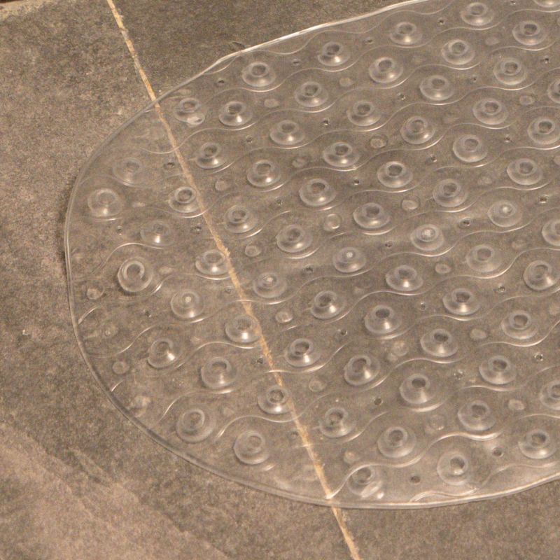 Transparent anti-slip capsule rubber shower mat on gray tiled bathroom floor