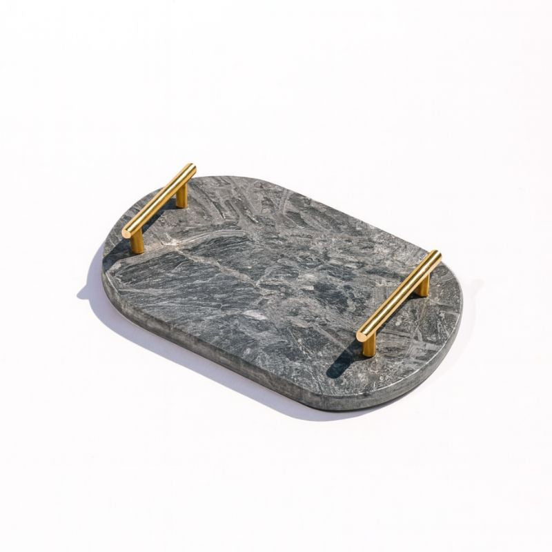 dark grey oval capsule-shaped marble tray with brass handles placed by the pool