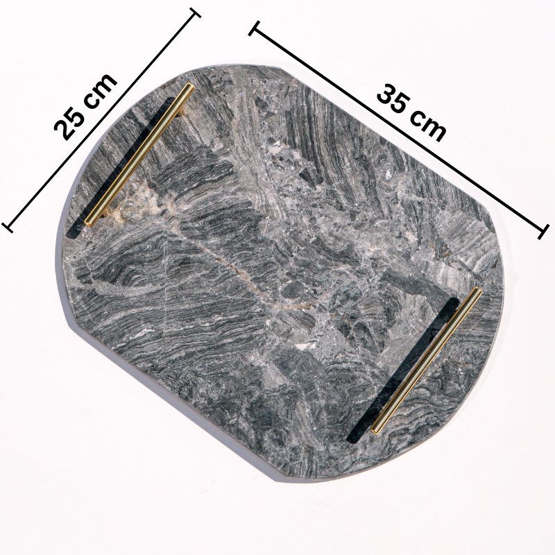 dark grey oval capsule-shaped marble tray with brass handles placed by the pool