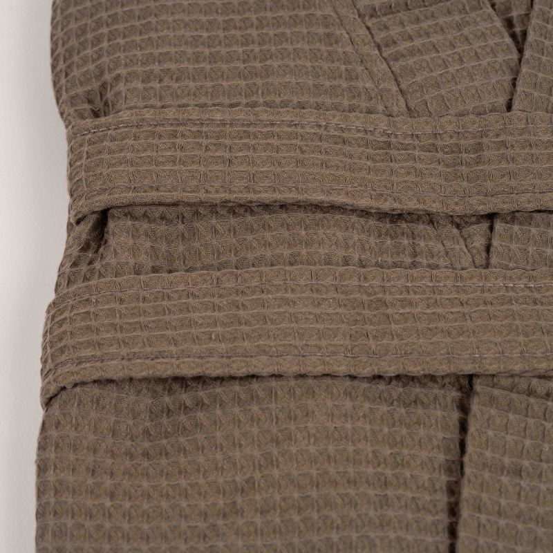 Greige waffle cotton bathrobe with belt and front pockets worn by woman on a balcony