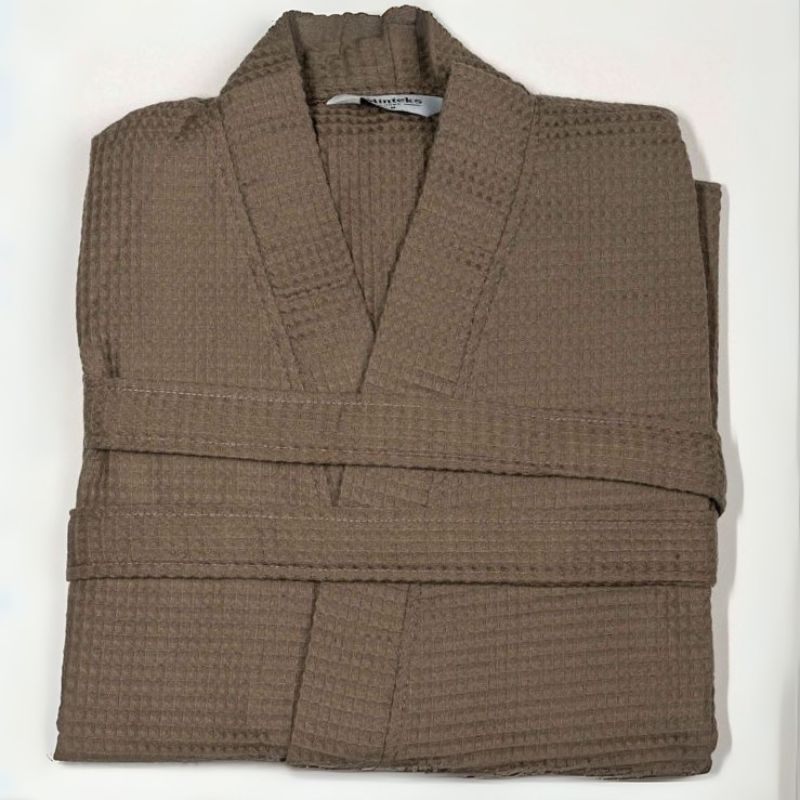 Greige waffle cotton bathrobe with belt and front pockets worn by woman on a balcony