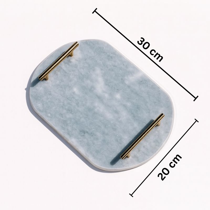 Light grey oval capsule-shaped marble tray with brass handles placed by the pool