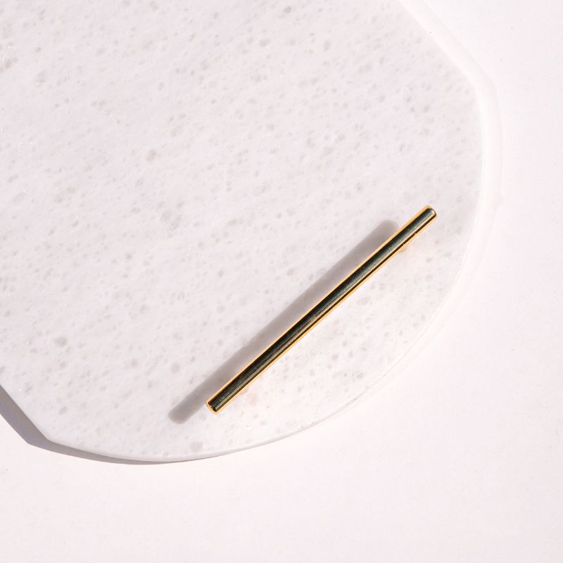 White oval capsule-shaped marble tray with brass handles placed by the pool