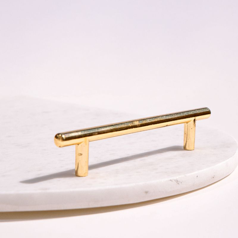 White oval capsule-shaped marble tray with brass handles placed by the pool