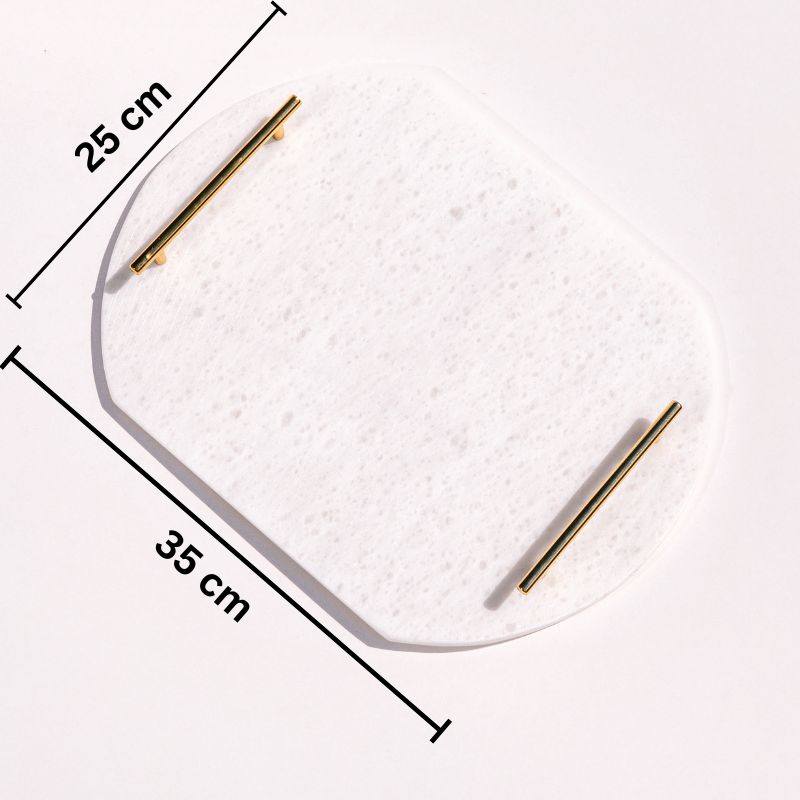 White oval capsule-shaped marble tray with brass handles placed by the pool