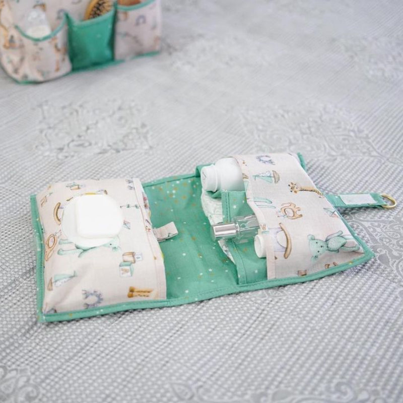 Foldable baby changing mat with built-in storage pockets and diapers, shown above a baby lying on a soft mat