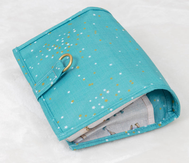 Foldable baby changing mat with built-in storage pockets and diapers, shown above a baby lying on a soft mat