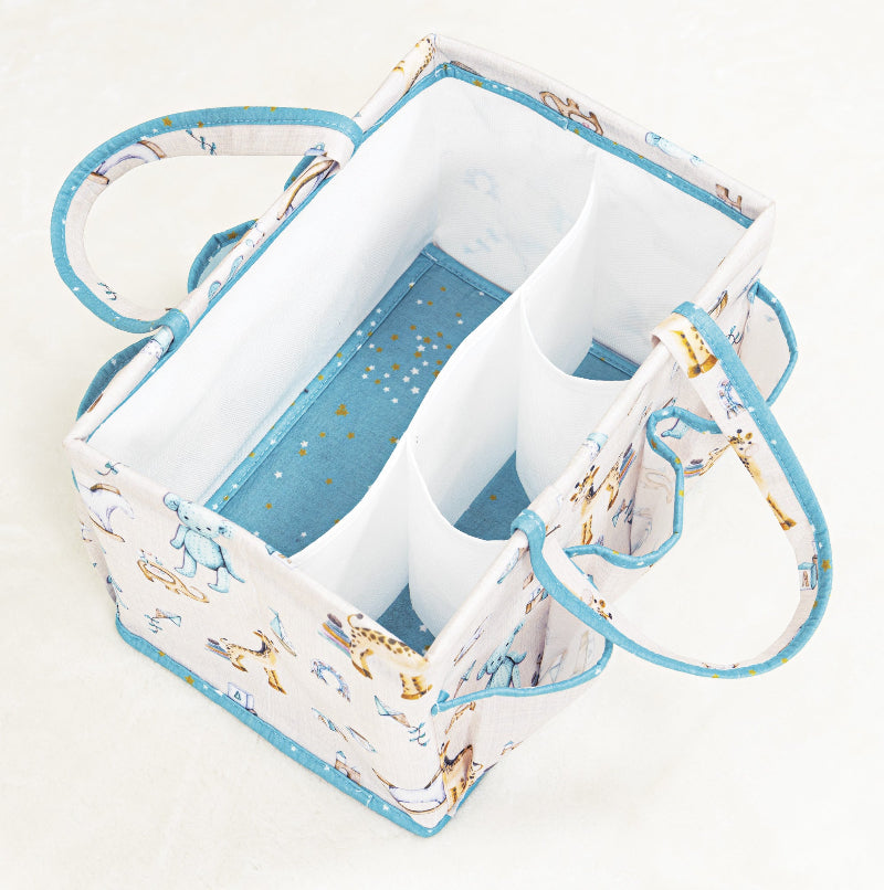 Portable baby diaper caddy organizer with compartments, filled with bottles, wipes, diapers, and teddy bear