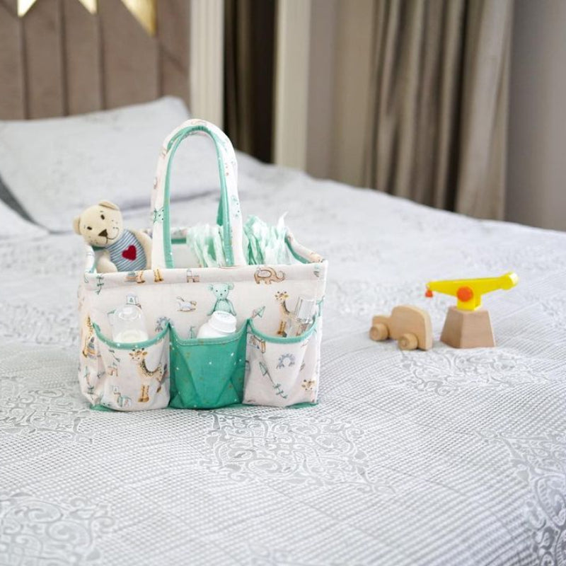 Portable baby diaper caddy organizer with compartments, filled with bottles, wipes, diapers, and teddy bear