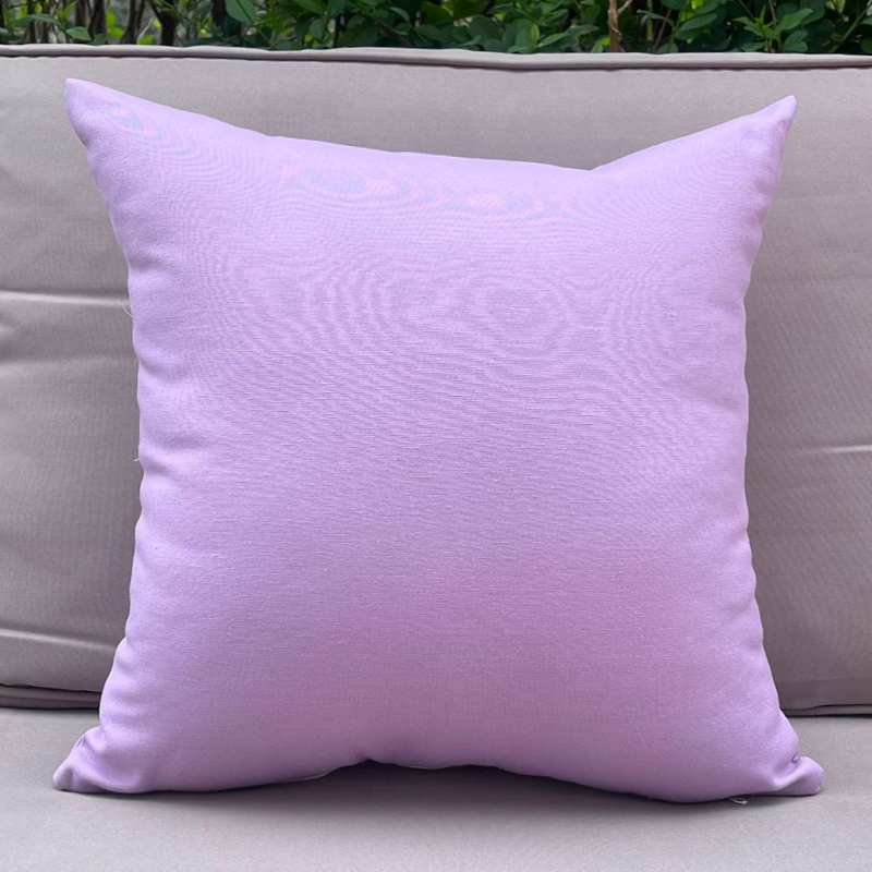 Lavender cushion cover displayed on a beige outdoor sofa in a garden patio setting