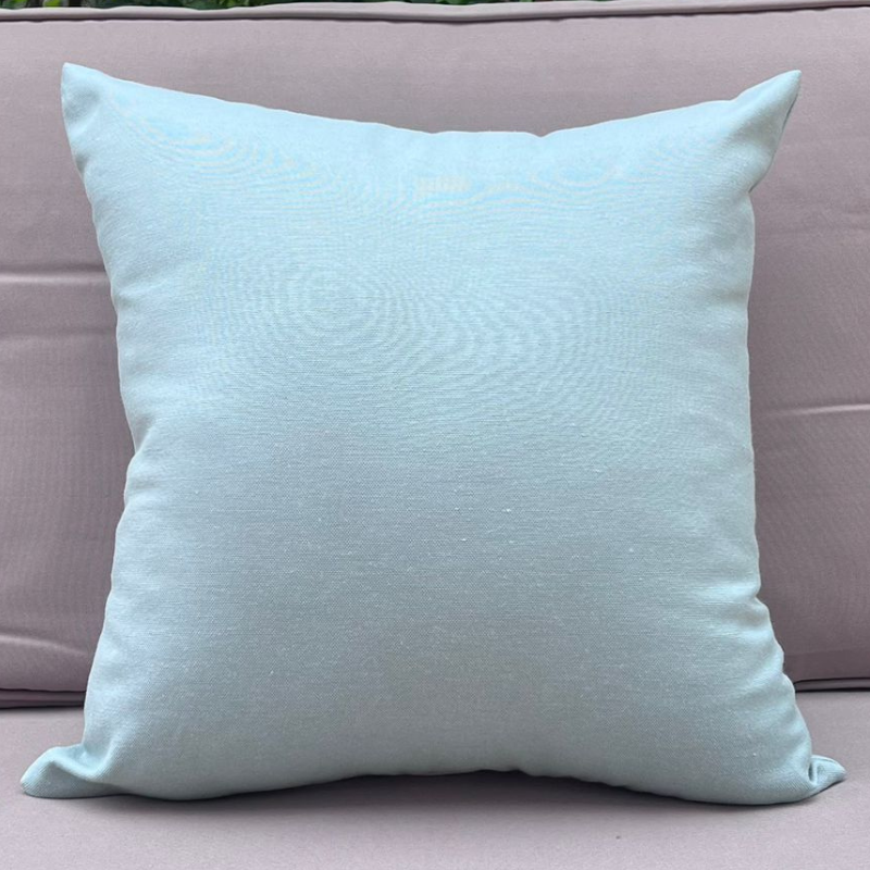 Mint cushion cover displayed on a beige outdoor sofa in a garden patio setting