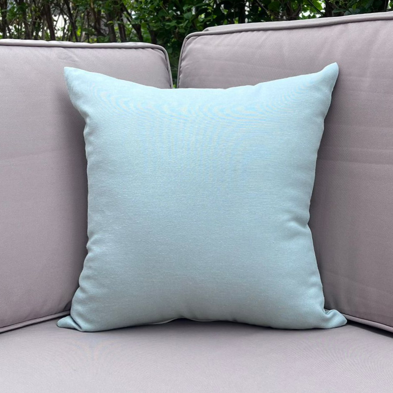 Mint cushion cover displayed on a beige outdoor sofa in a garden patio setting