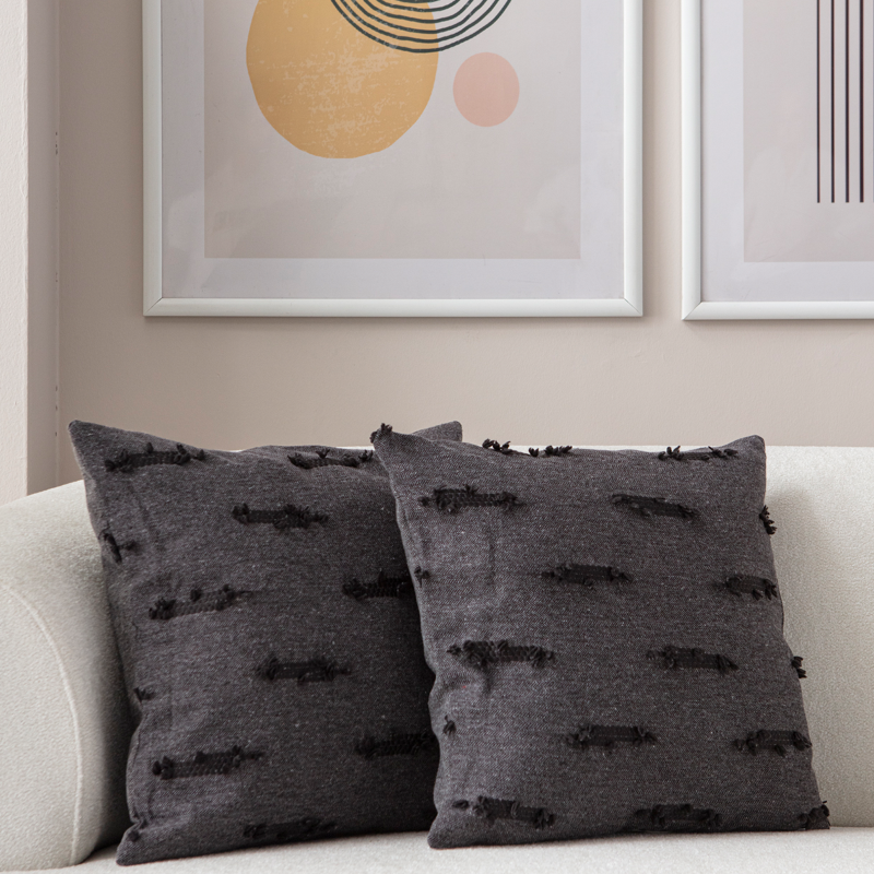 Dark charcoal textured woven throw pillow on light sofa – decorative cushion with horizontal tufted accents