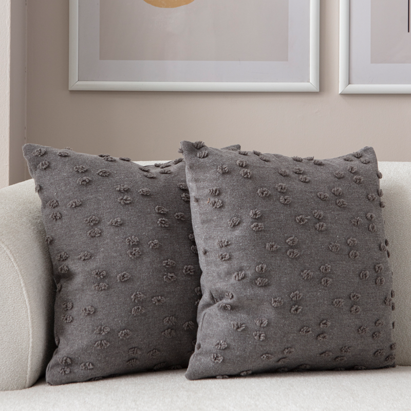 Charcoal textured tufted throw pillow on light sofa – modern decorative cushion
