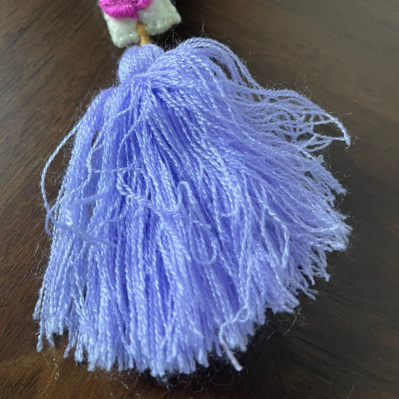 Handmade embroidered letter P ornament with colorful floral embroidery and lavender tassel on wooden background