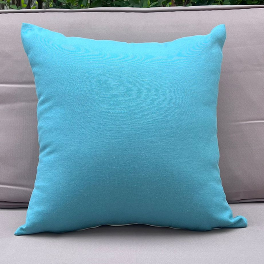 Aqua blue cushion cover displayed on a beige outdoor sofa in a garden patio setting