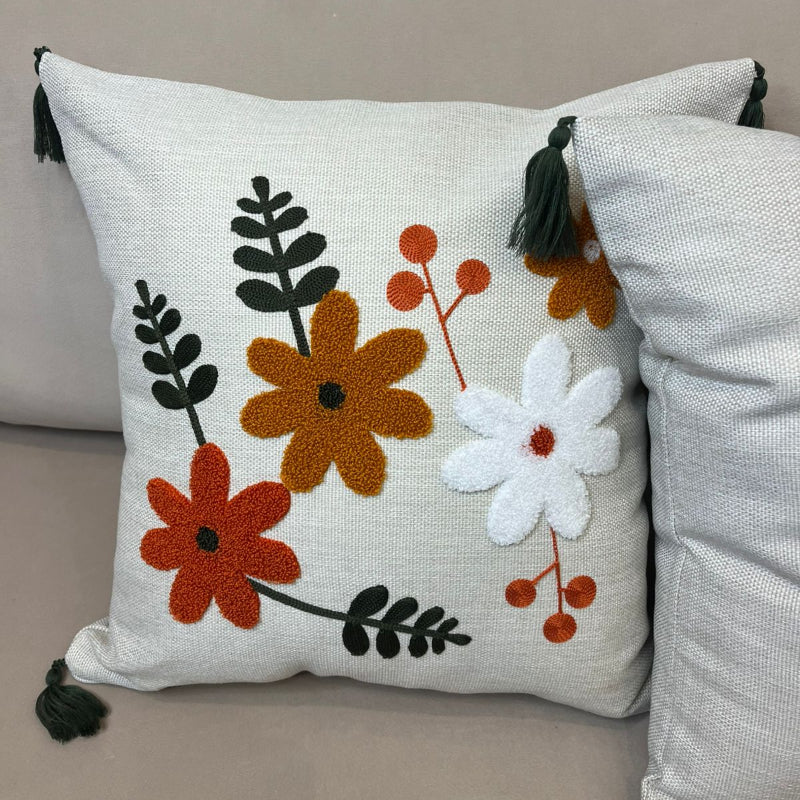 Multicolor embroidered floral cushion cover with tassels on beige sofa