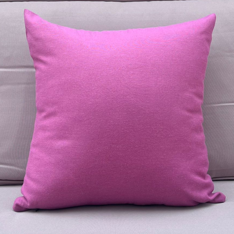 Purple cushion cover displayed on a beige outdoor sofa in a garden patio setting