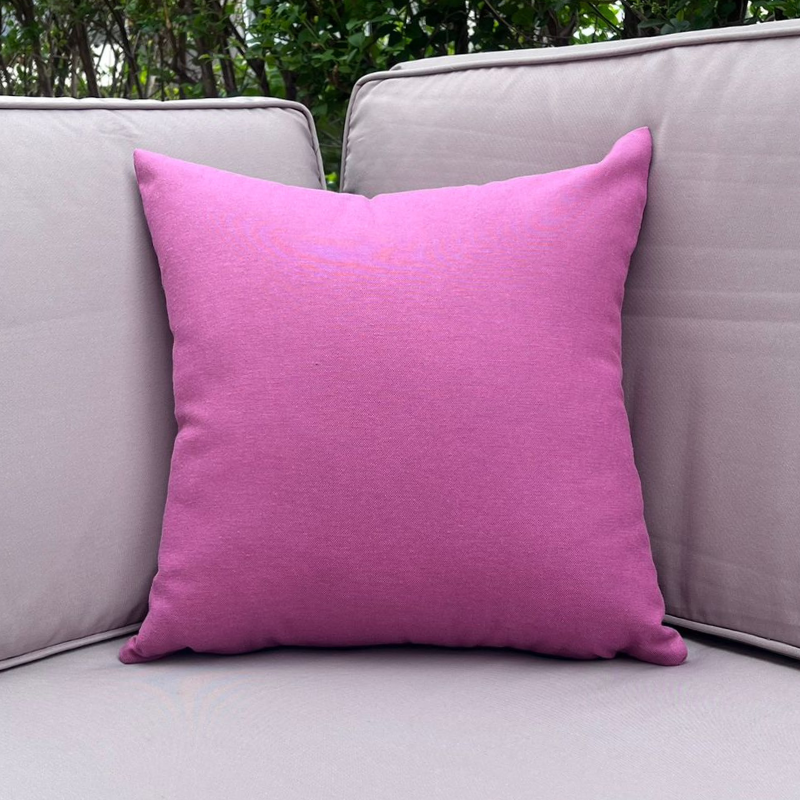 Purple cushion cover displayed on a beige outdoor sofa in a garden patio setting