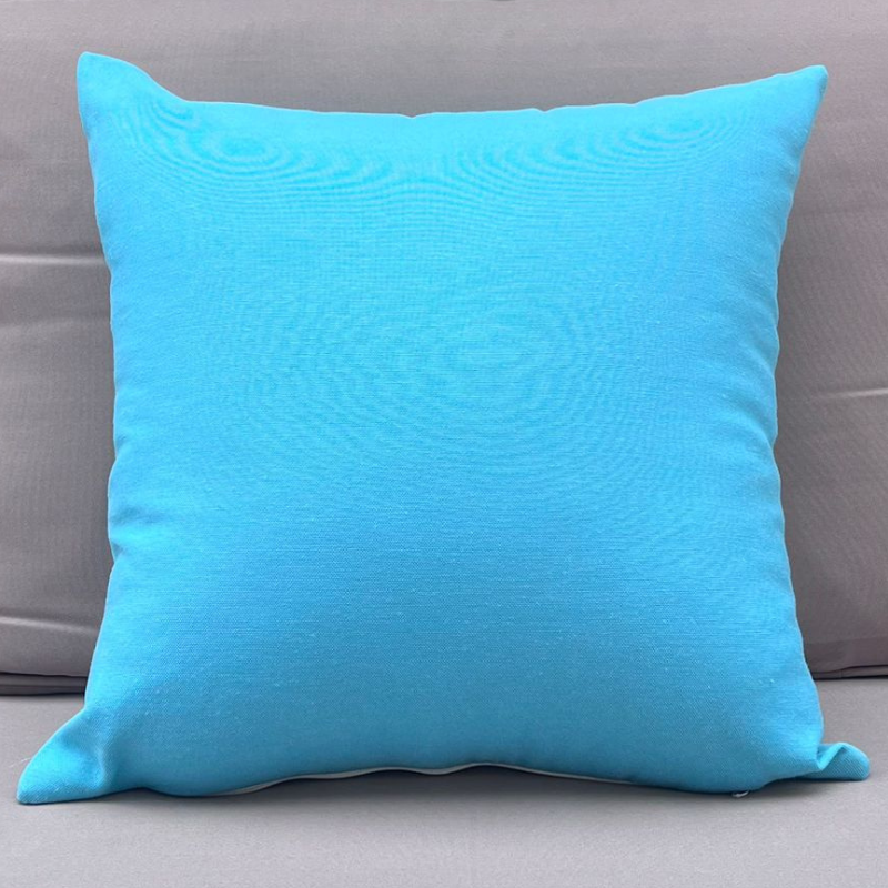 Turquoise cushion cover displayed on a beige outdoor sofa in a garden patio setting