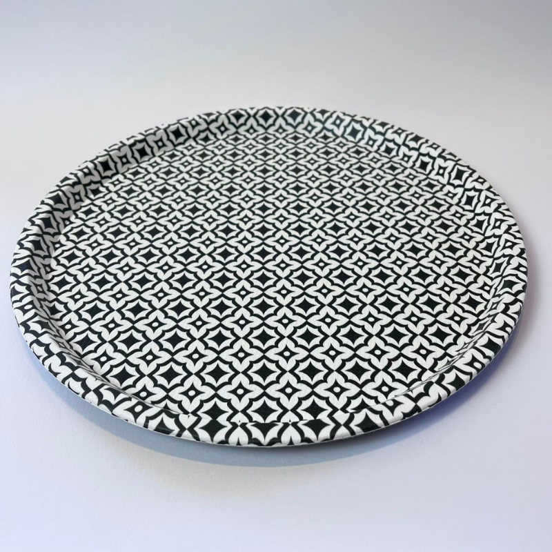 Round ceramic plate with black geometric pattern on a white background