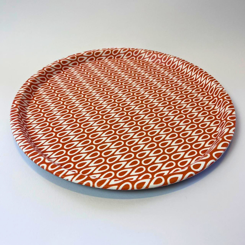 Round plate with a red and white pattern on a light gray background
