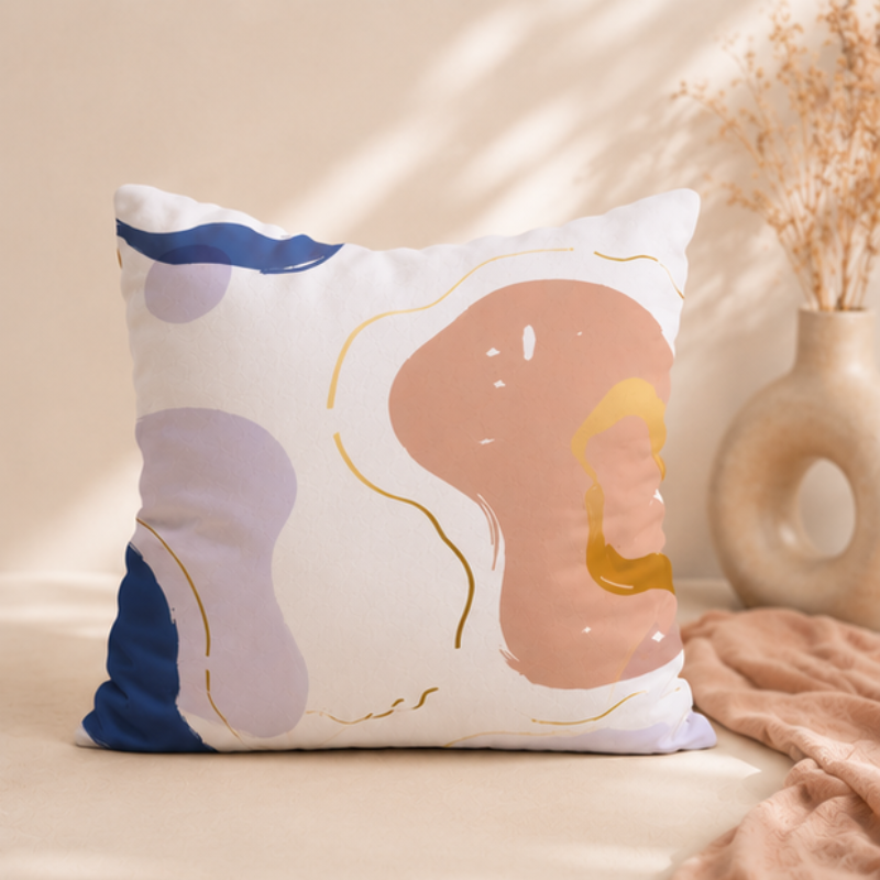 Neutral cushion cover with abstract shapes in beige, blue, and soft gold accents on a modern decorative pillow