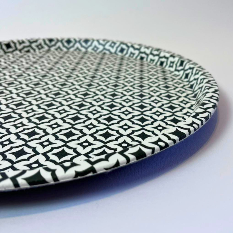 Round ceramic plate with black geometric pattern on a white background