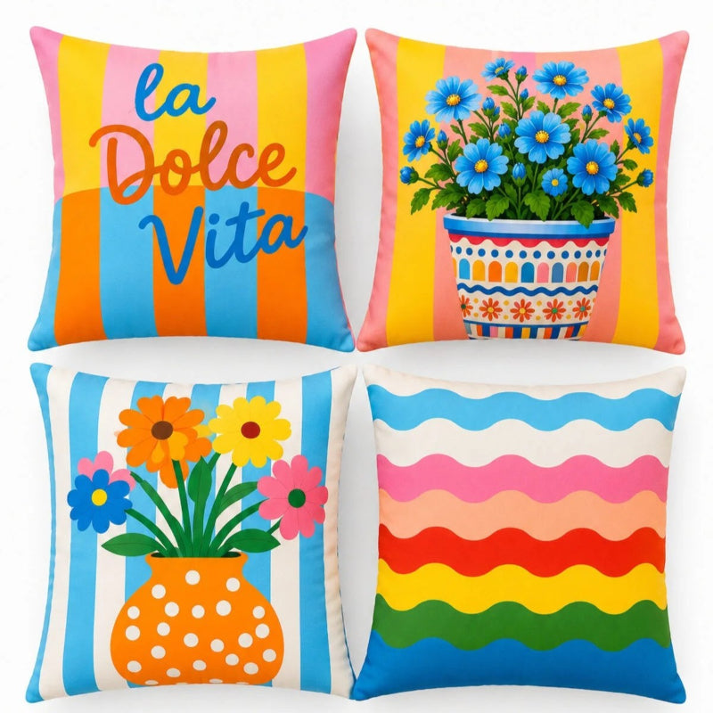Set of four colorful Mediterranean-inspired decorative cushion covers featuring "La Dolce Vita" typography, floral ceramic planters, striped backgrounds, and a vibrant rainbow wave pattern displayed on a modern cream sofa.