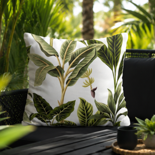 White cushion with green tropical leaves in a botanical pattern design