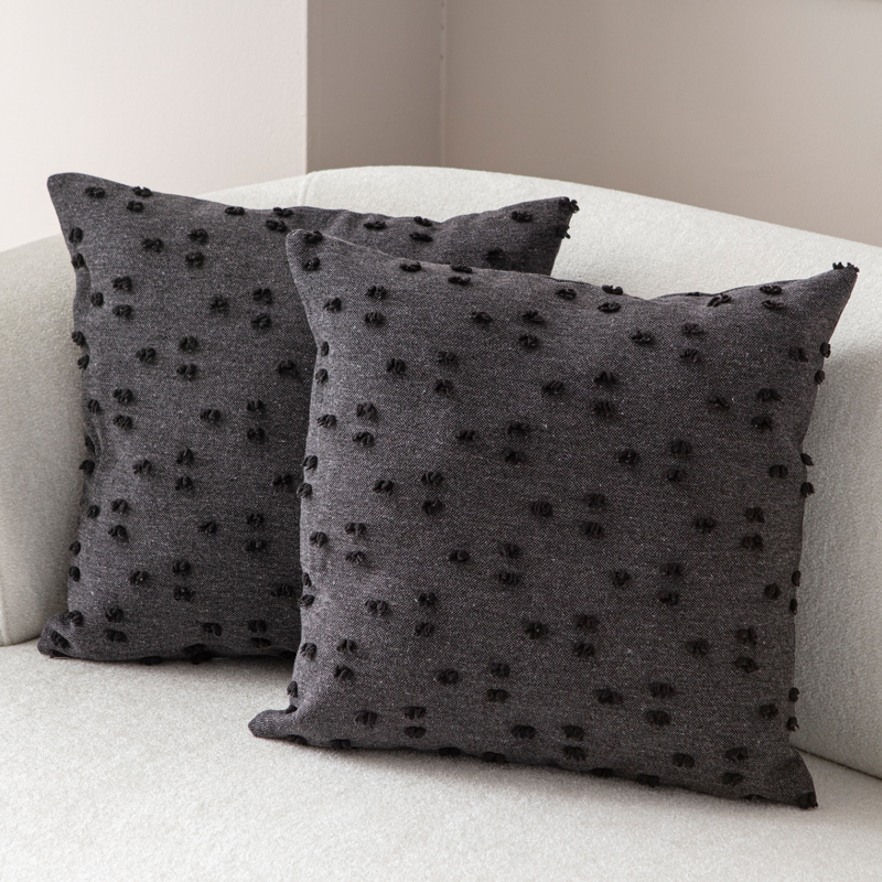 Dark charcoal tufted throw pillow on light sofa – textured decorative cushion