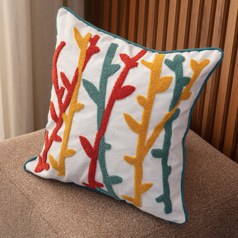 Cream cushion cover with colorful tufted abstract botanical embroidery in teal, mustard, and red