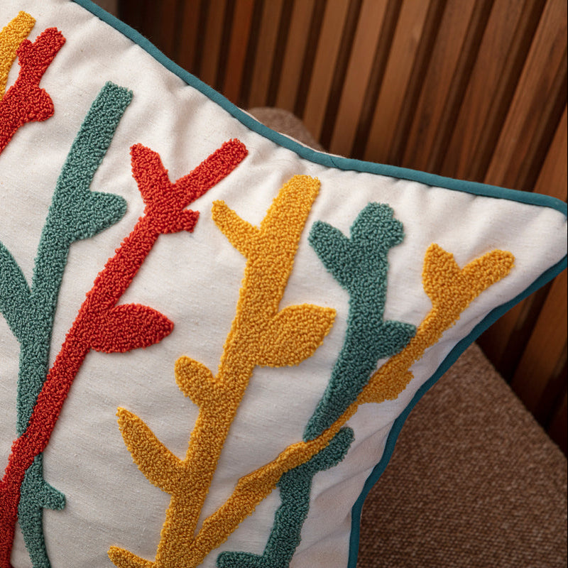 Cream cushion cover with colorful tufted abstract botanical embroidery in teal, mustard, and red