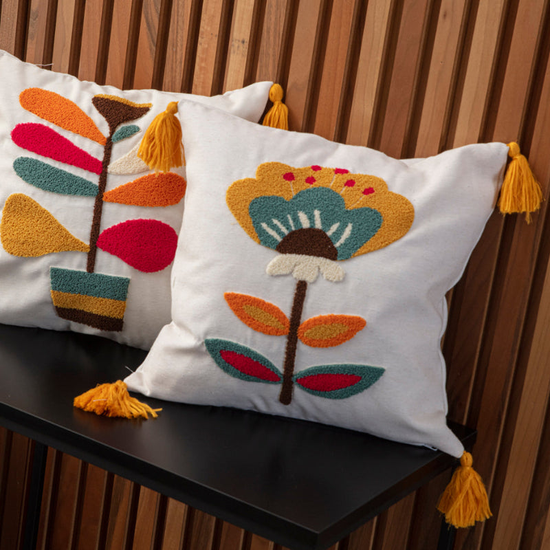 Cream cushion cover with tufted floral embroidery in mustard, teal, red, and yellow tassels