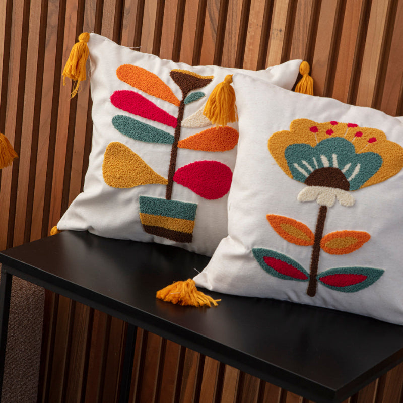 Cream cushion cover with colorful tufted leaf embroidery and yellow tassels on each corner