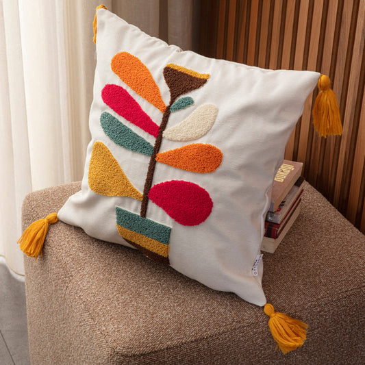 Cream cushion cover with colorful tufted leaf embroidery and yellow tassels on each corner