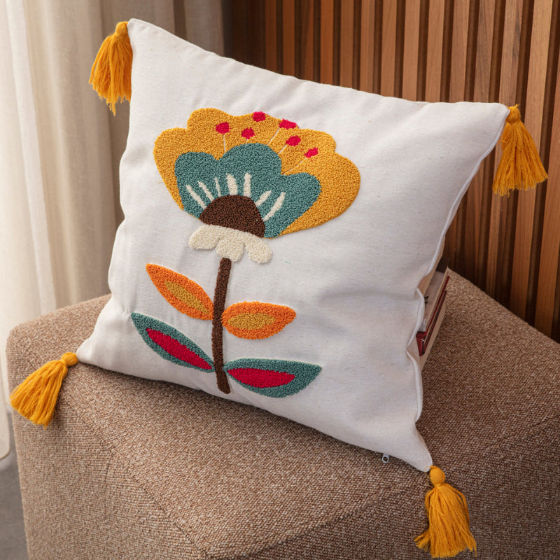 Cream cushion cover with tufted floral embroidery in mustard, teal, red, and yellow tassels