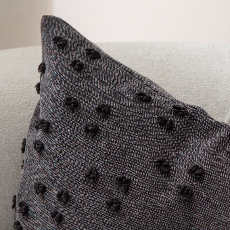 Dark charcoal tufted throw pillow on light sofa – textured decorative cushion